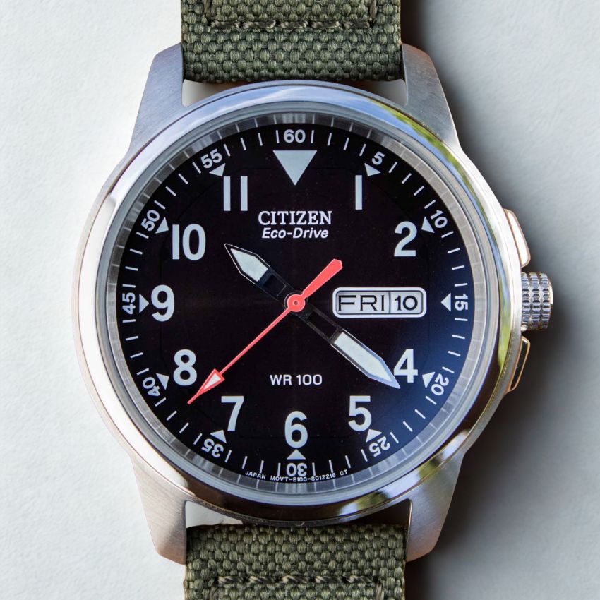 Close-up of military field watch with green nylon strap for durability